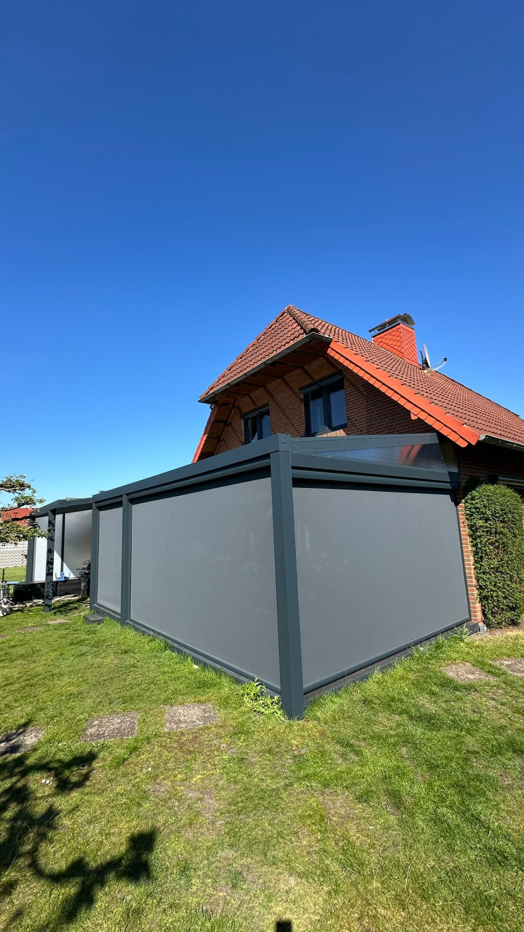 Terrassenüberdachung mit grauen Senkrechtmarkisen rundum als Sicht- und Windschutz