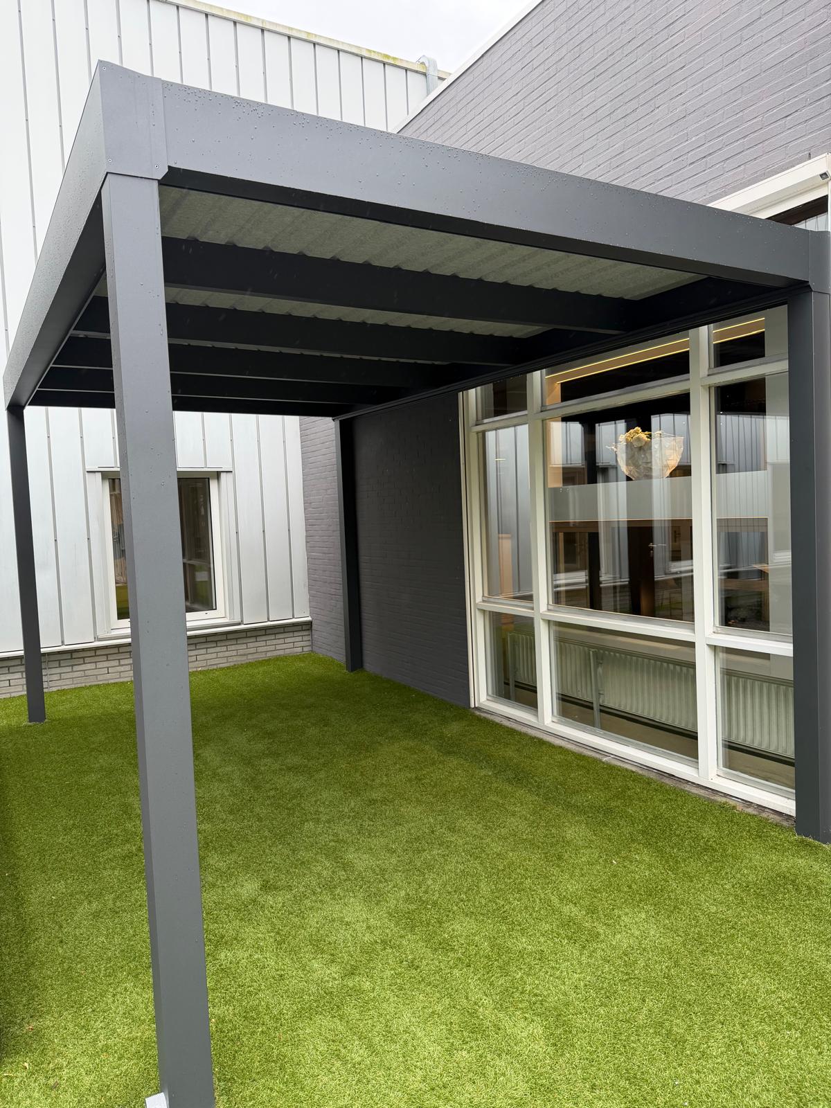 Carport aus anthrazitfarbenem Aluminium mit Flachdach an einer Hauswand