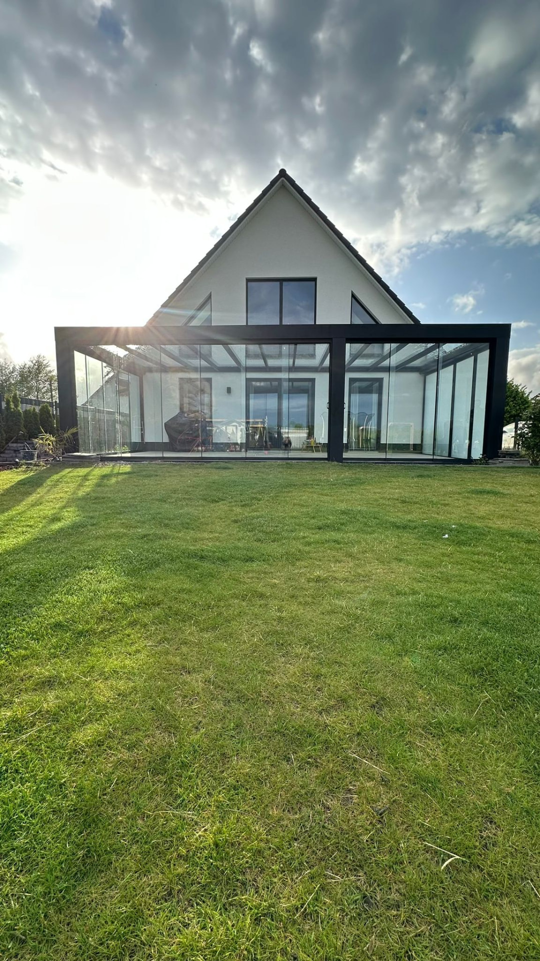 Große Cube Überdachung mit Glasfront an einem weißen Einfamilienhaus