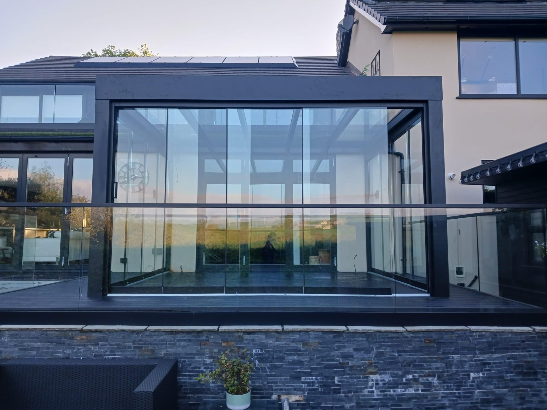 Cube Überdachung mit umlaufender Verglasung auf einer Holzterrasse