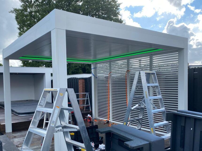 Weiße Lamellenpergola mit farbiger LED-Beleuchtung und ZIP-Screen während der Montage