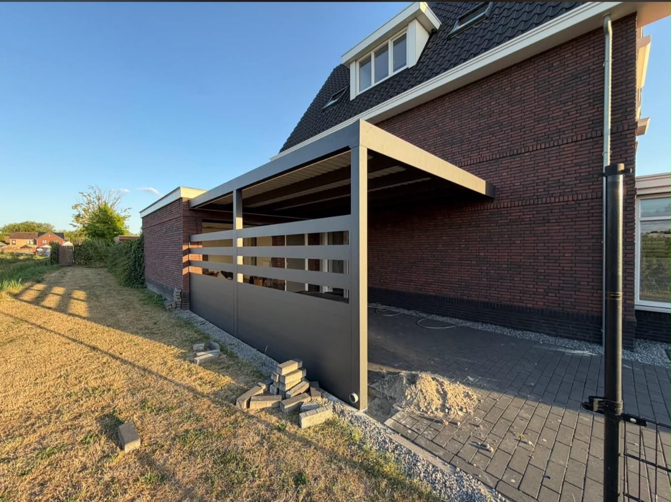 Carport an einem Klinkerhaus mit Lamellen-Seitenwand