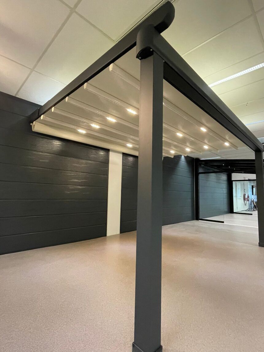 Anthrazitfarbene bioklimatische Pergola mit geschlossenen Lamellen und LED-Spots in der Ausstellung