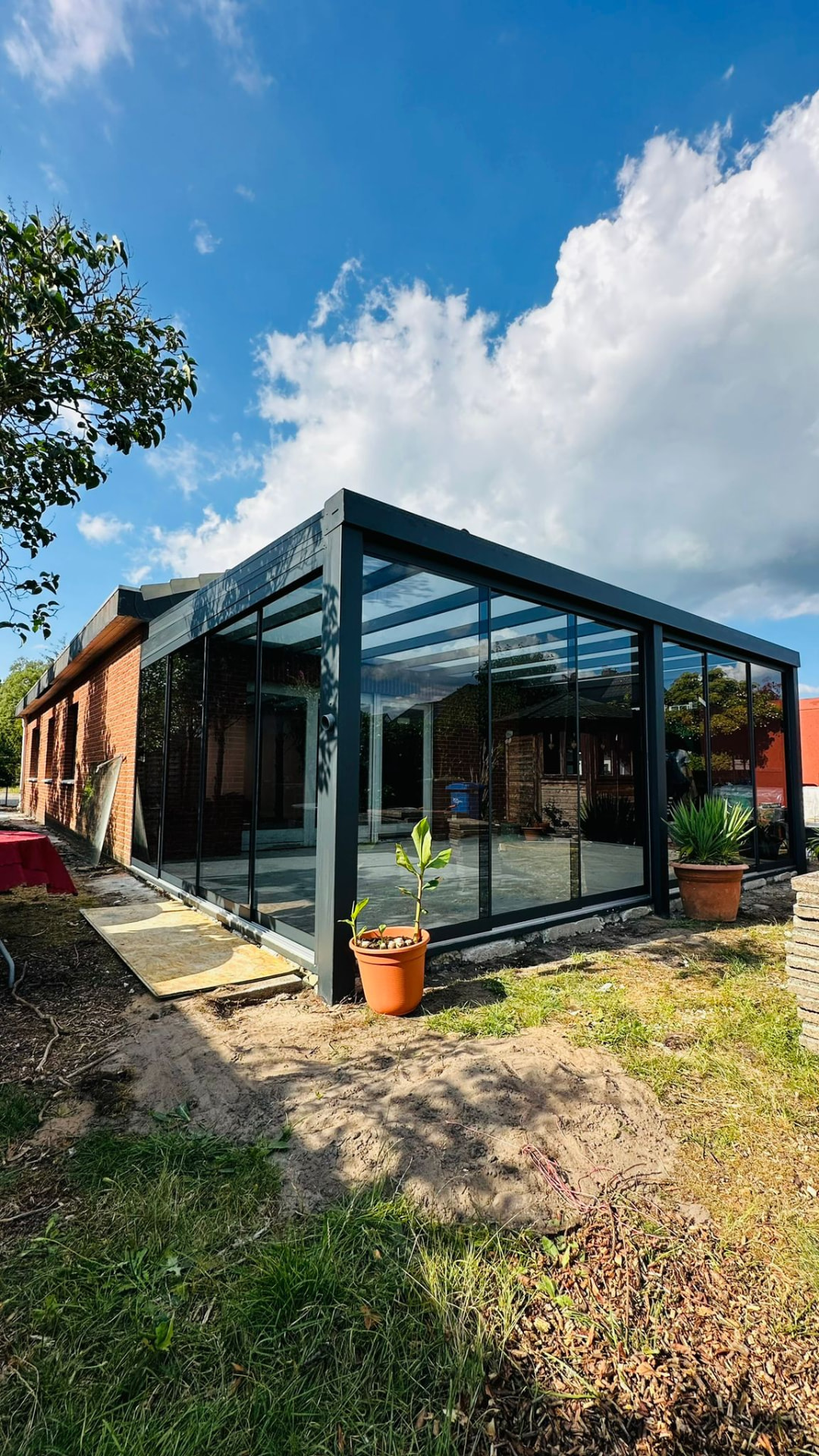 Verglaste Terrassenüberdachung mit Glas-Schiebeelementen an einem Klinkerbau