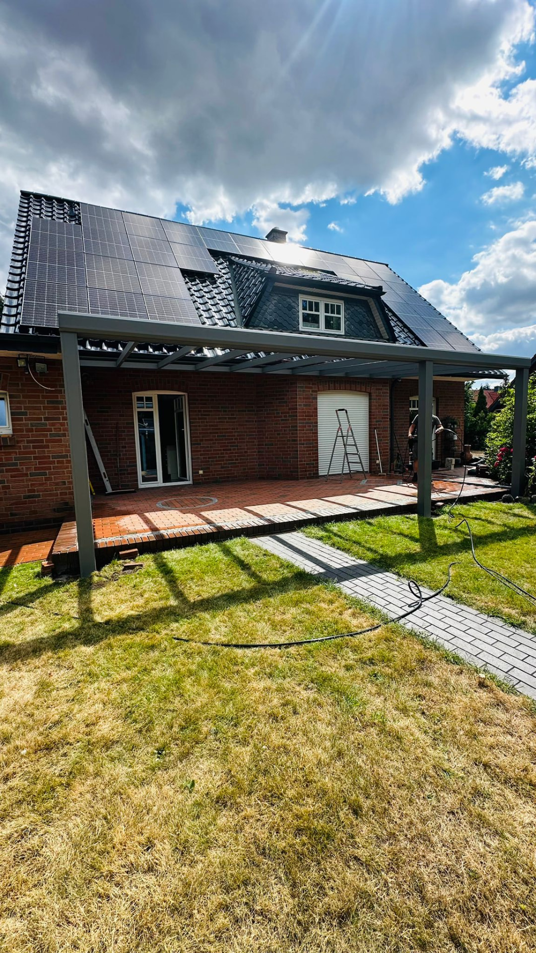 Terrassenüberdachung mit Glasdach an einem Klinkerhaus mit Photovoltaik